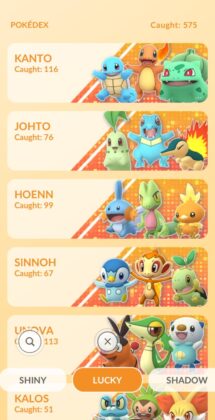 New updated Pokémon GO Lucky Pokédex. It is light orange, with POKEDEX Caught: 876 at the top. Underneath are three banners for Kanto, Johto, Hoenn, Sinnoh, Unova and Kalos, each show the regions three starter Pokémon jumping happily.