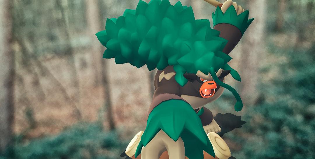 A Rillaboom swings their arm towards the camera as if it is hitting you, the other arm is raised above their head to continue their attack, they are roaring. Behind them is a woodland that is out of focus