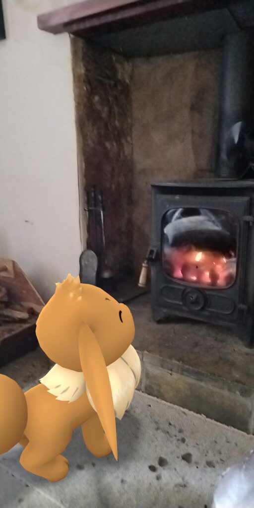 A Pikachu looks at a traditional wood fire with a happy expression