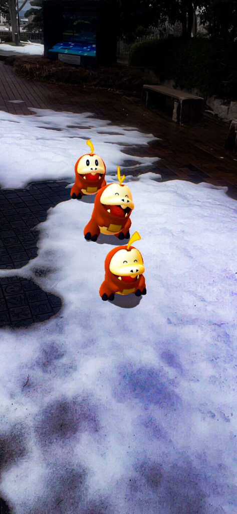 Three Fuecoco walk in a line following each other on a snowy path