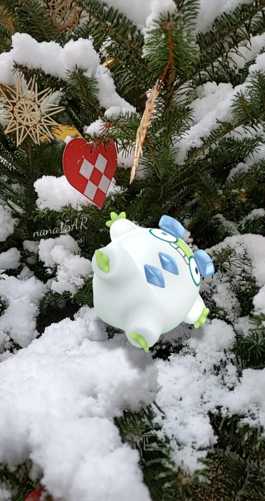 A shiny Galarian Darumaka has fallen over in the snow on a fir tree