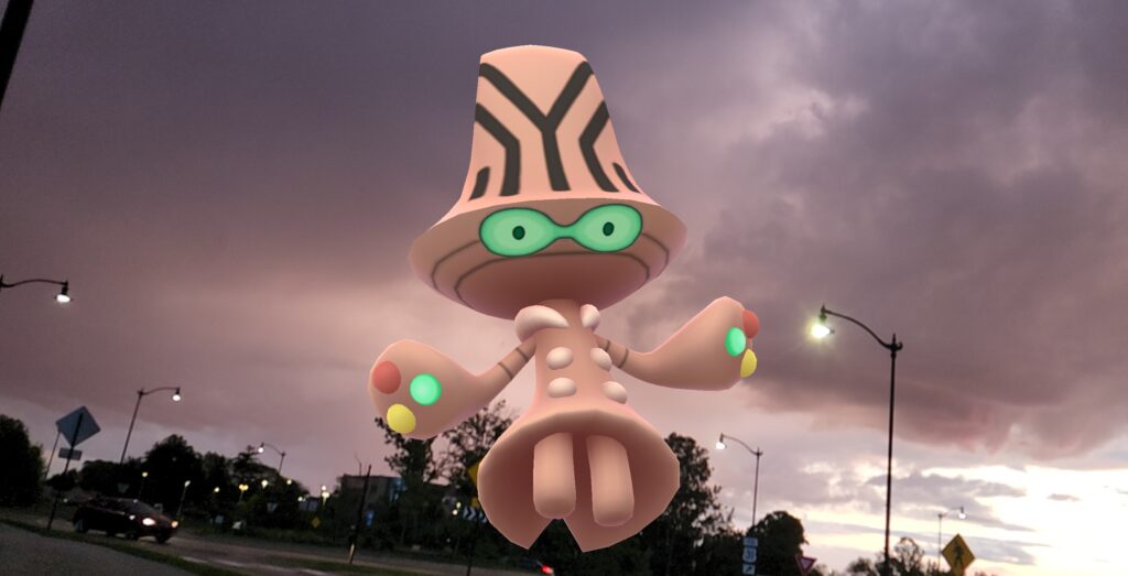 A Beeheeyem against a stormy night sky with street lights behind it